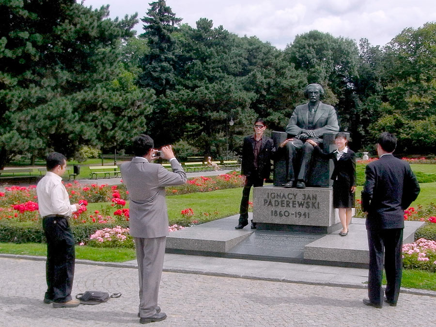 Pomnik Ignacego Padarewskiego w parku Ujazdowskim na którego tle fotografują się turyści  azjatyccy